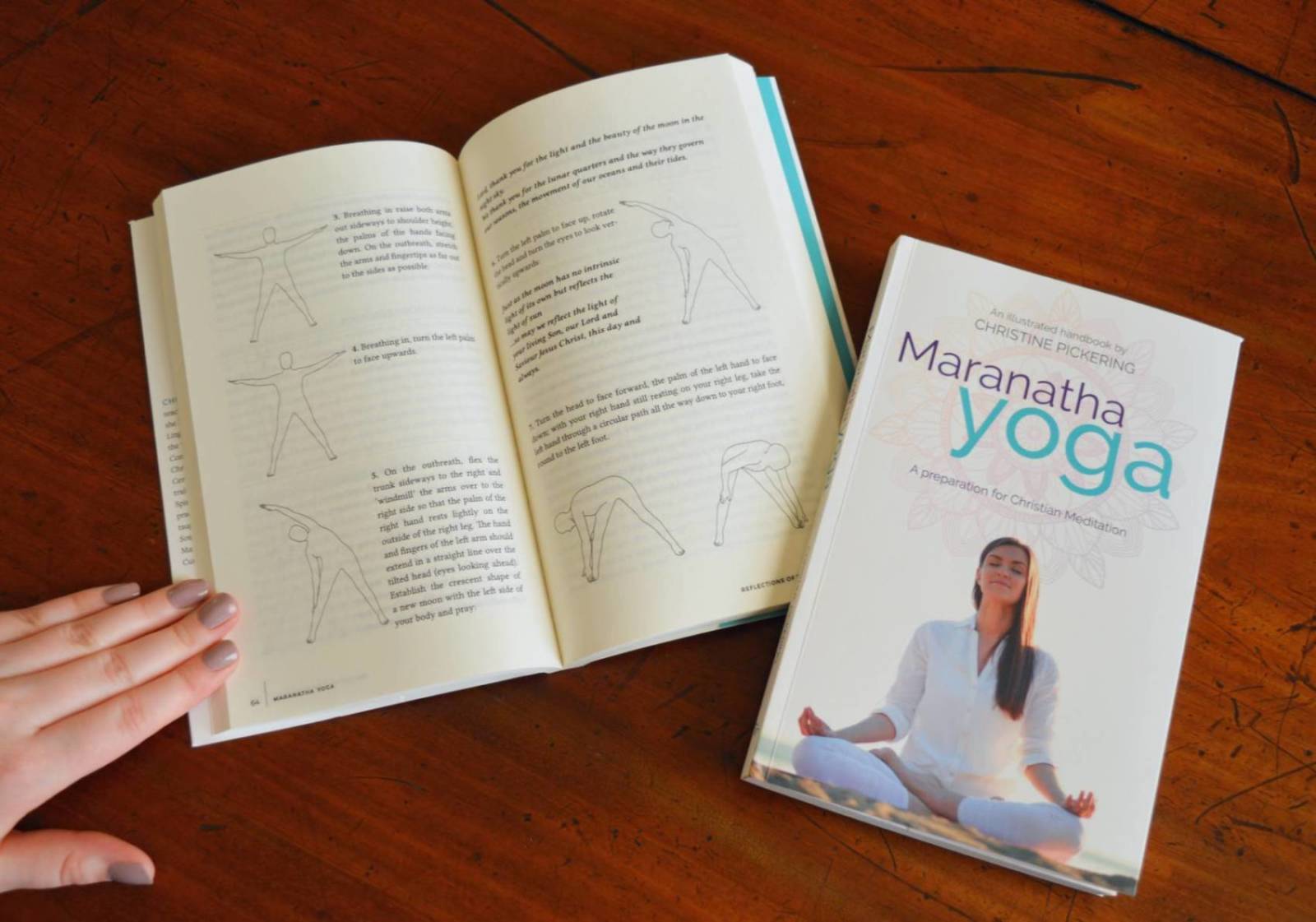 Maranatha Yoga book held open by hand, next to a closed copy